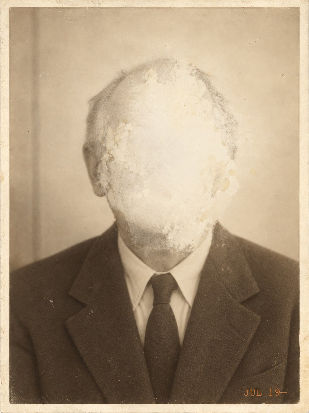 An old sepia portrait of the former proprietor in a jacket and tie; damp has lifted the emulsion over his face
